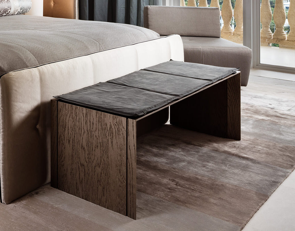 Vienna Bench with dark wood and upholstered seating at end of light-colored bed frame