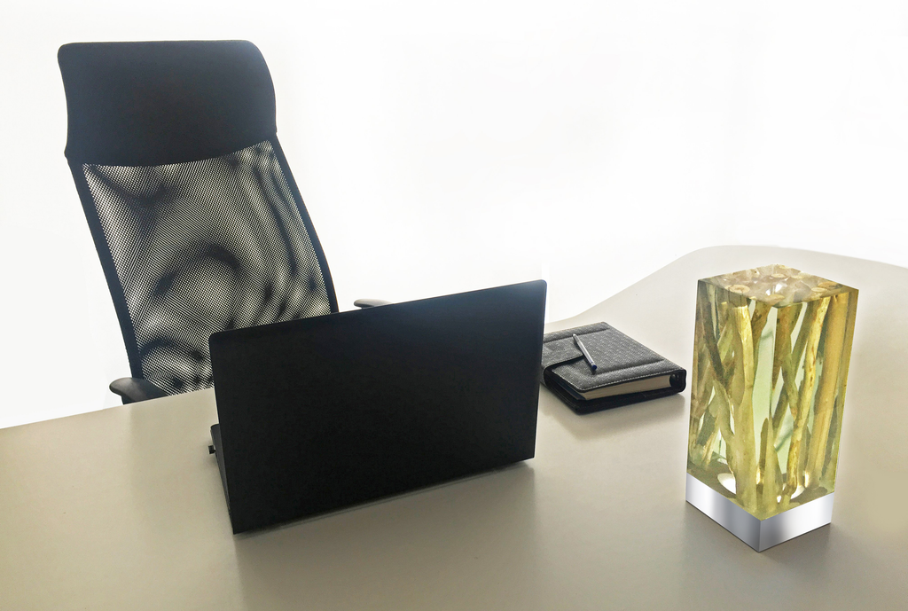 Modern office desk setup with branches cube table lamp, black mesh chair, laptop, and leather planner