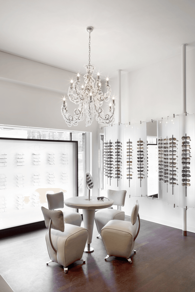 Well-lit room with Coco Chandelier Conical, crystal chandelier, round table, and eyeglasses display