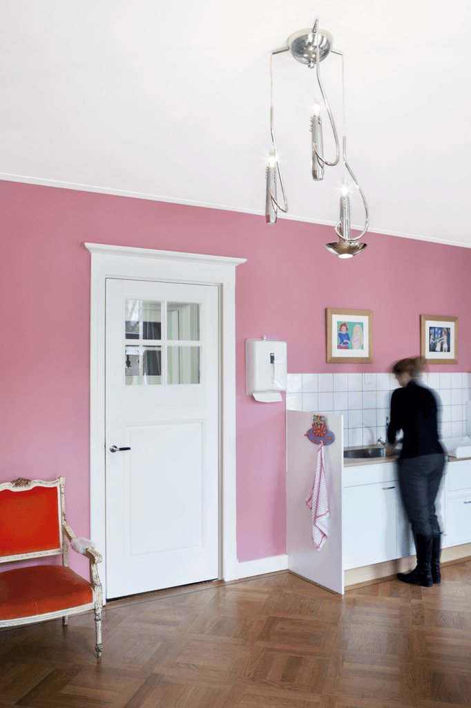 Bright pink room with white door and modern chandelier featuring floating candles hanging lamp