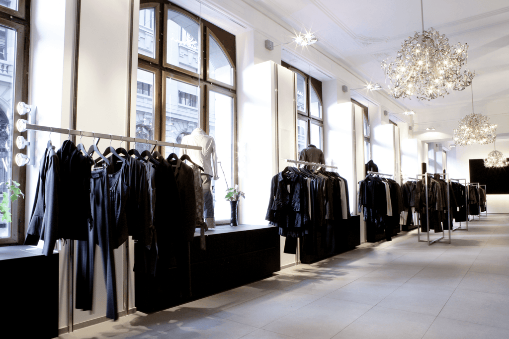 Spacious clothing boutique with Flower Power Chandelier Round and dark garments