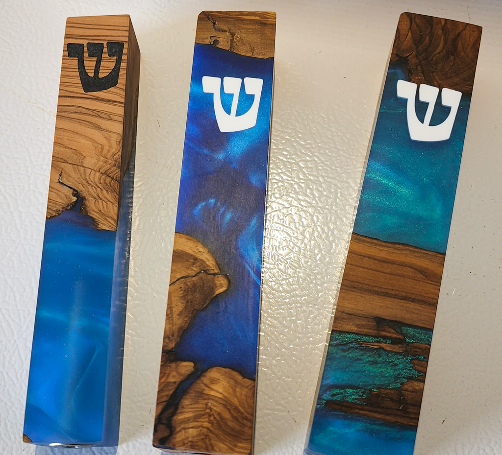 Modern mezuzah featuring three wooden blocks with blue resin and the Hebrew letter Shin